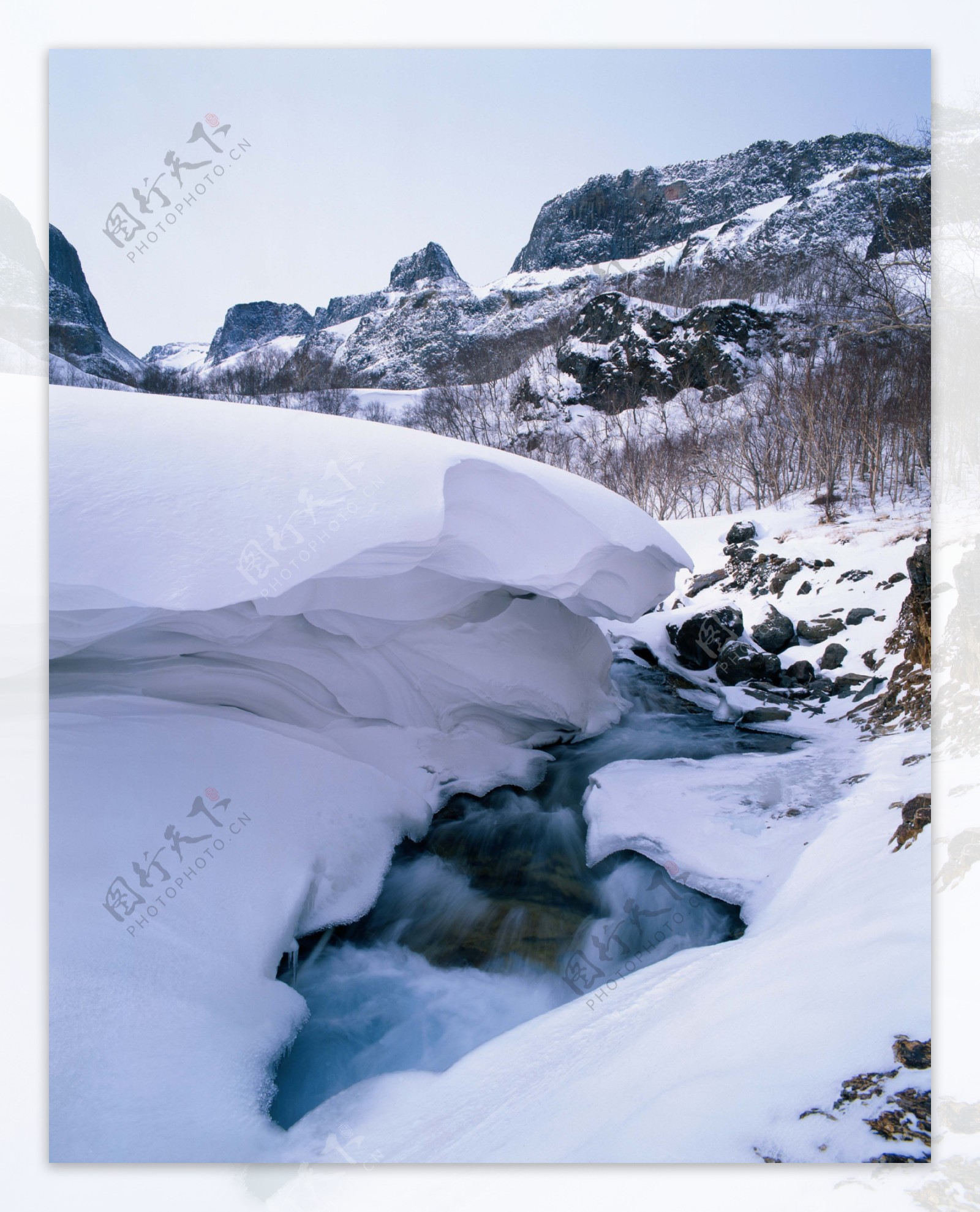 山间厚厚积雪旁流淌的小溪图片