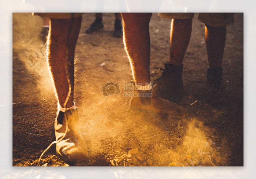 人穿着棕色靴子和白袜子站在泥地面尘土飞扬