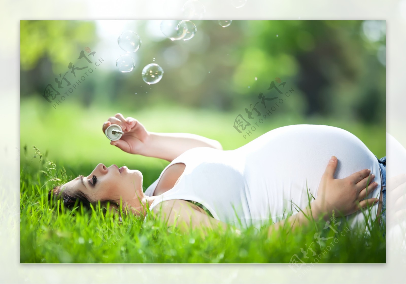 草地上吹泡泡的孕妇图片
