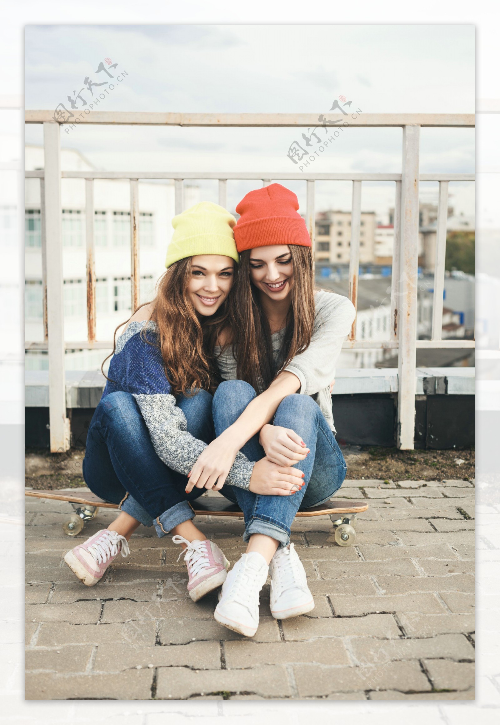 坐在滑板上的两个戴帽子美女图片