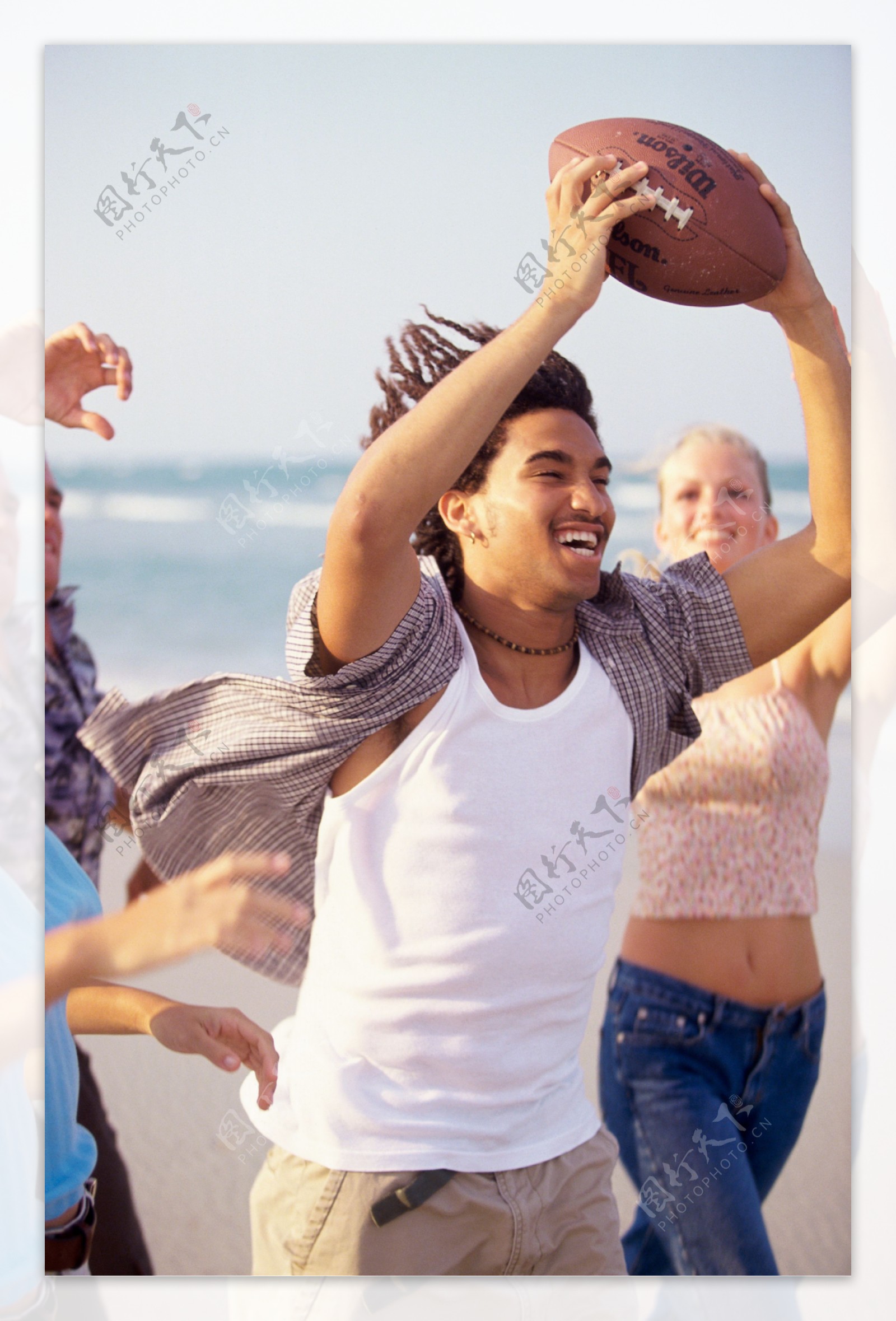 沙滩上打橄榄球的青年图片