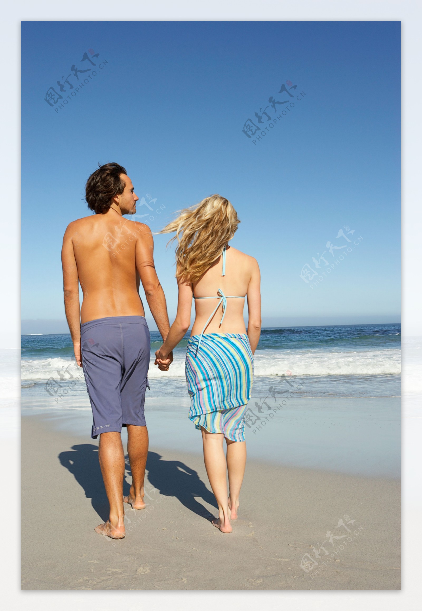 在海边牵手散步的夫妇图片