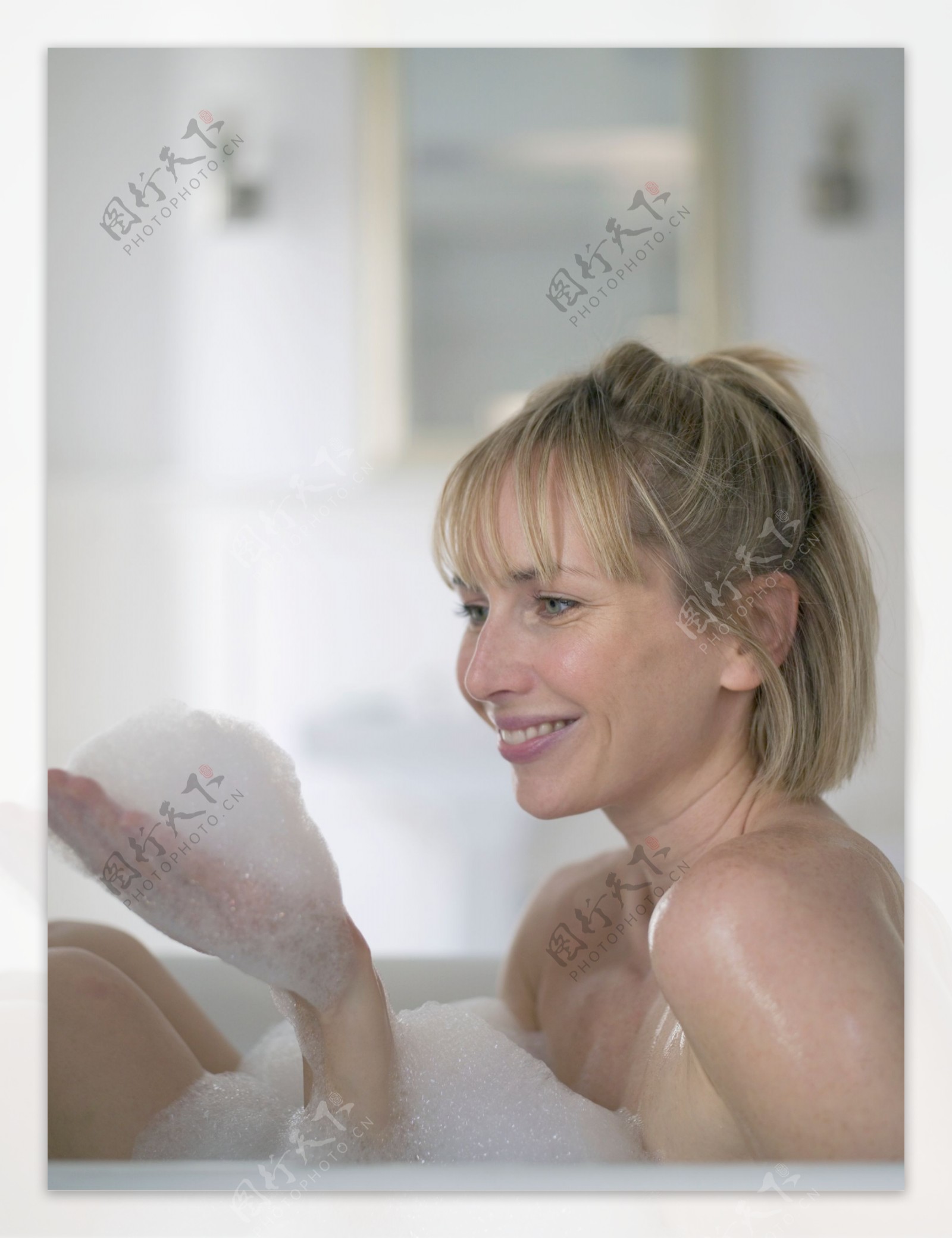浴缸里手捧白色泡沫的女人图片
