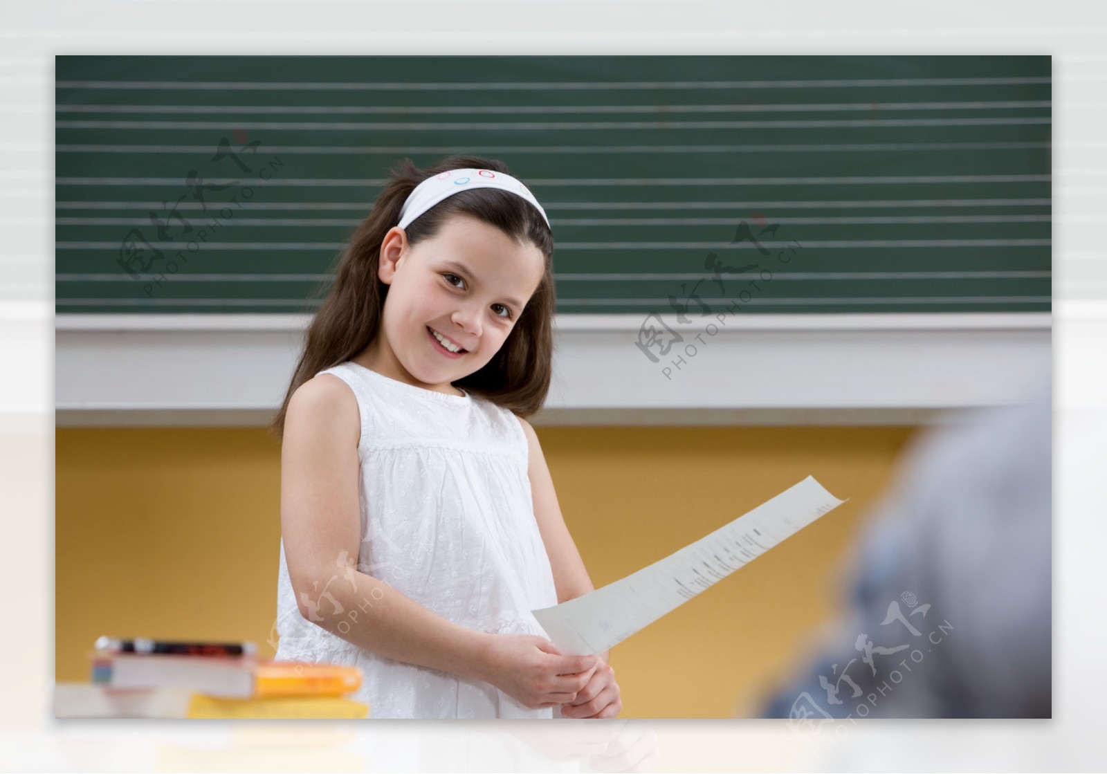 教室里拿着一张纸的小女孩图片