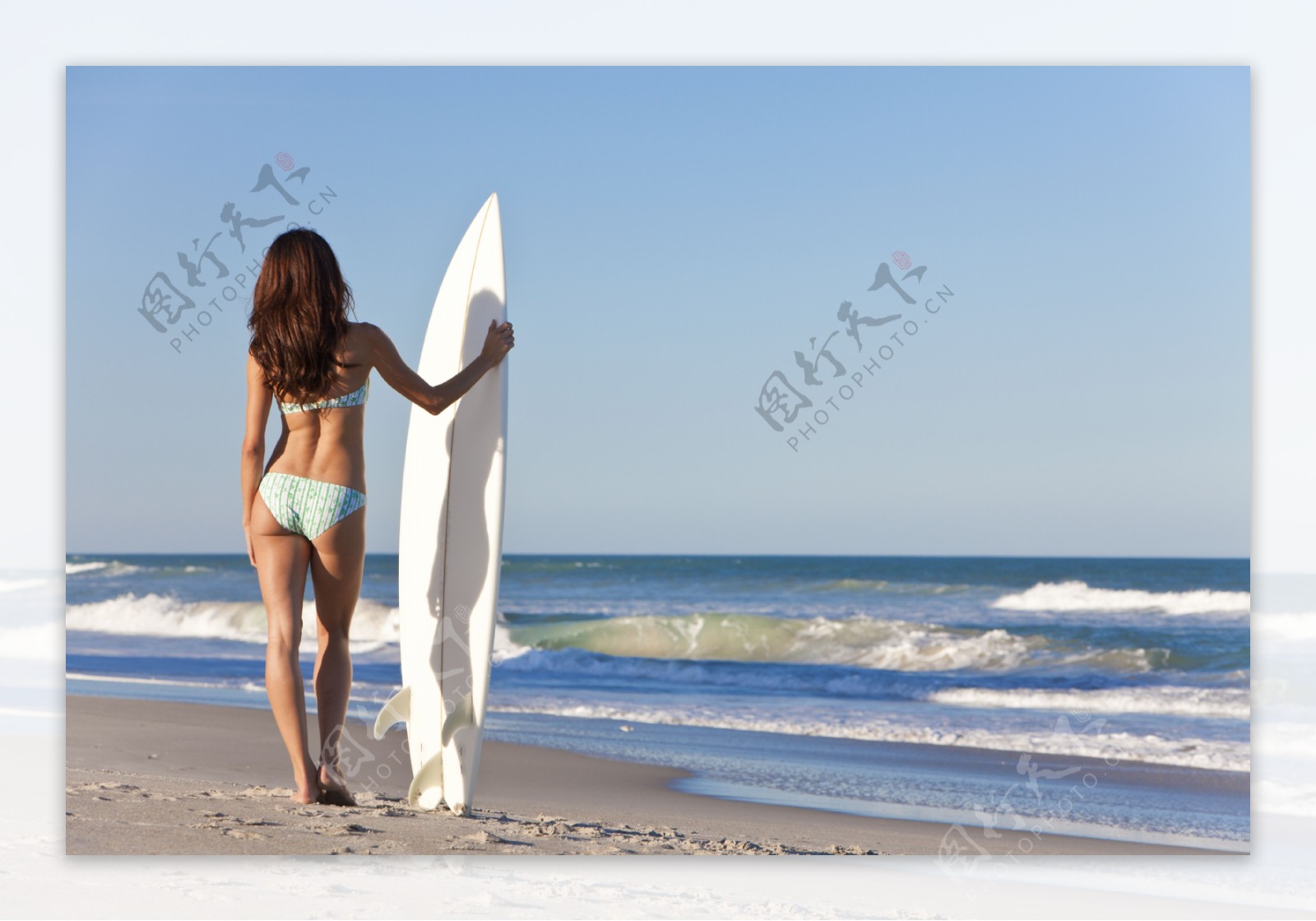 沙滩上拿着冲浪板的女人图片