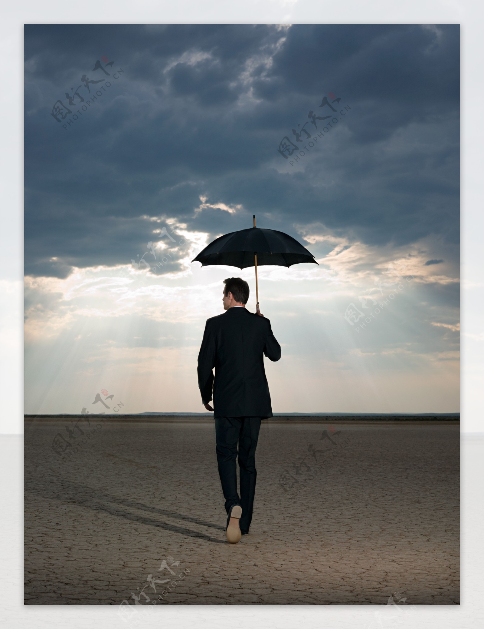 打着雨伞走在旱地里的外国男人图片